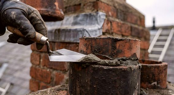 Trowel of fresh mortar set against a clay chimney pot